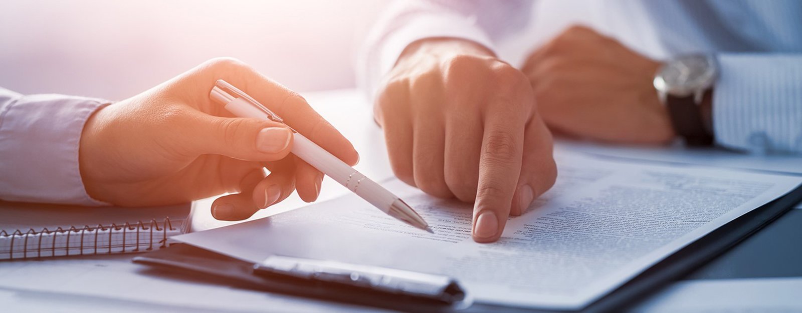 Two people at a table signing a contract